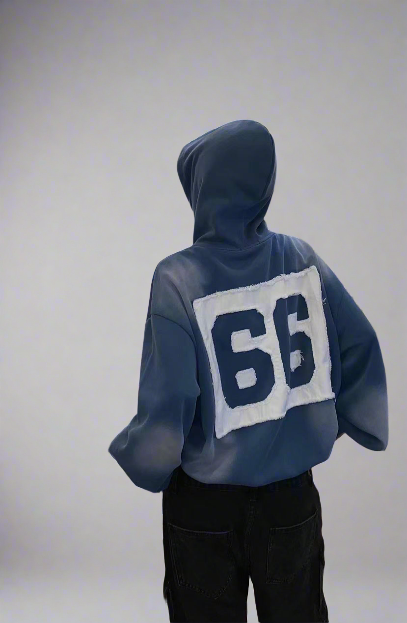 Person wearing a blue hoodie with the number 66 on the back against a plain background